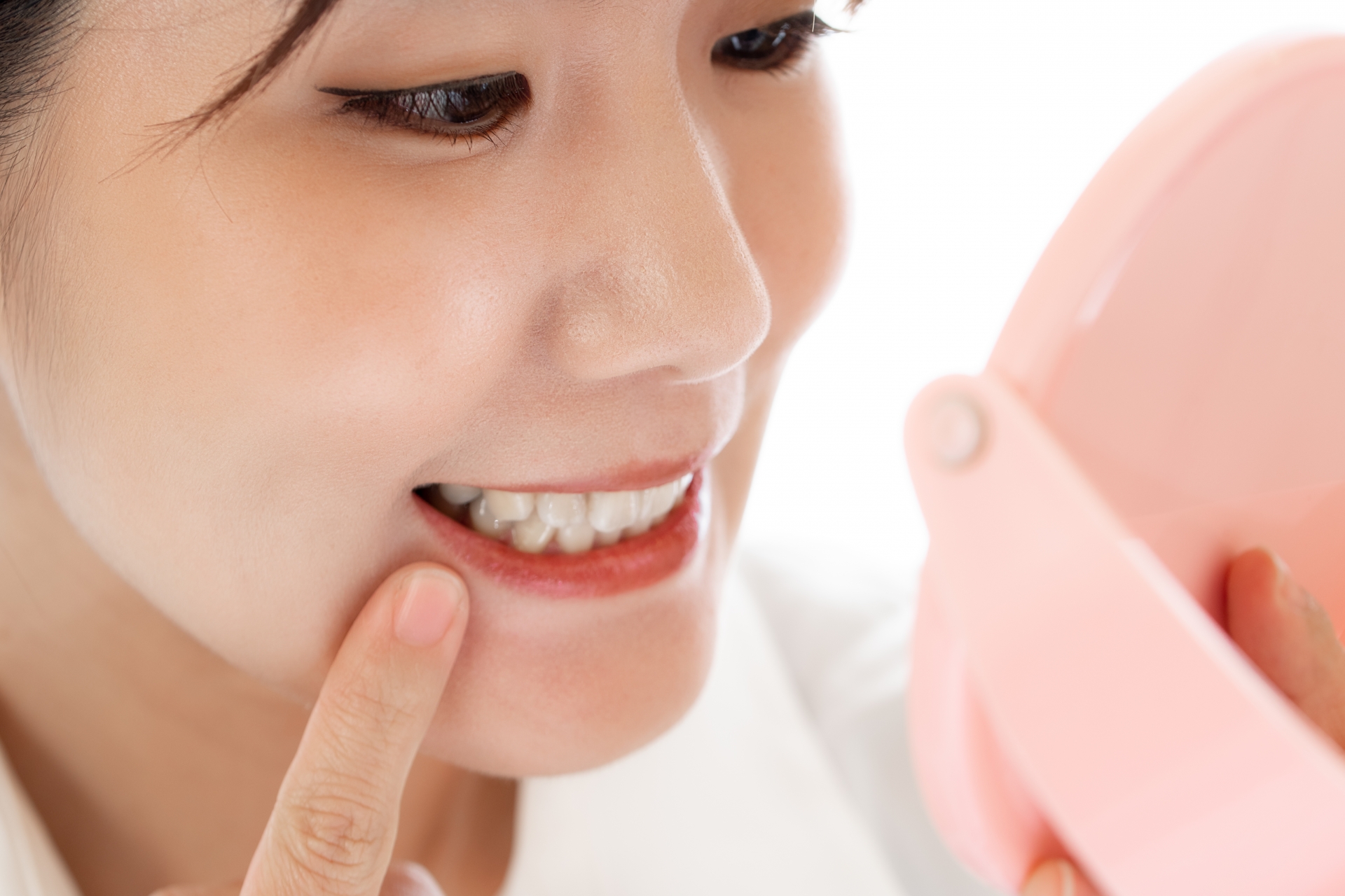 鏡で歯をチェックする日本人女性